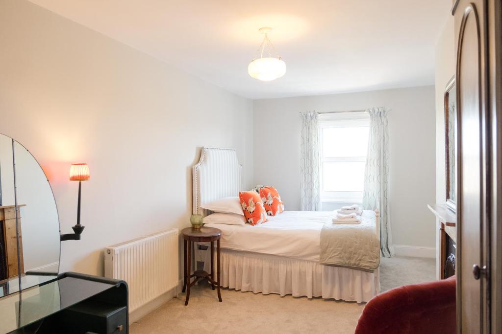 朴次茅斯Southsea, Portsmouth - Two Bedroom Apartment - Newly Refurbished Throughout - Treetop Sea Views的一间卧室配有带橙色枕头的床和窗户。