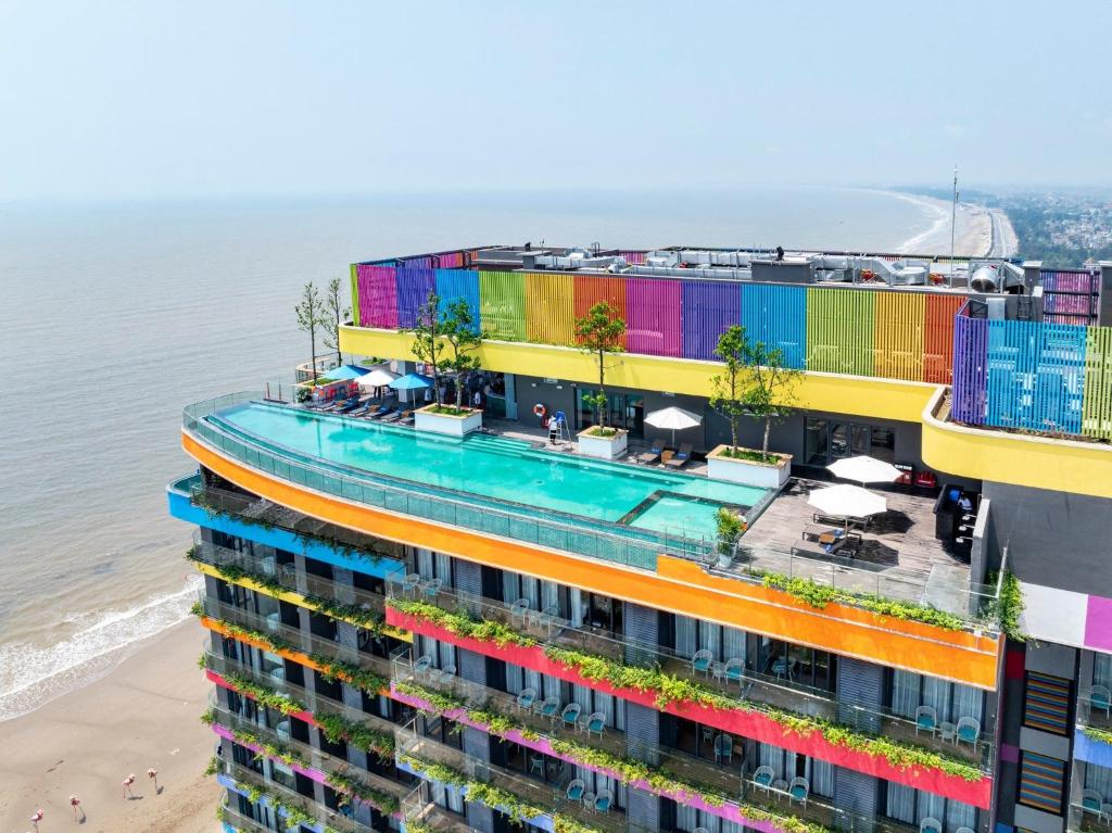 清化Flamingo Ibiza Hải Tiến的公寓大楼设有色彩缤纷的阳台,毗邻海滩