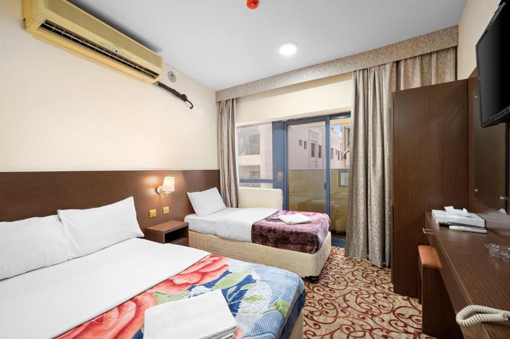 迪拜Najiba Hotel的酒店客房设有两张床和电视。