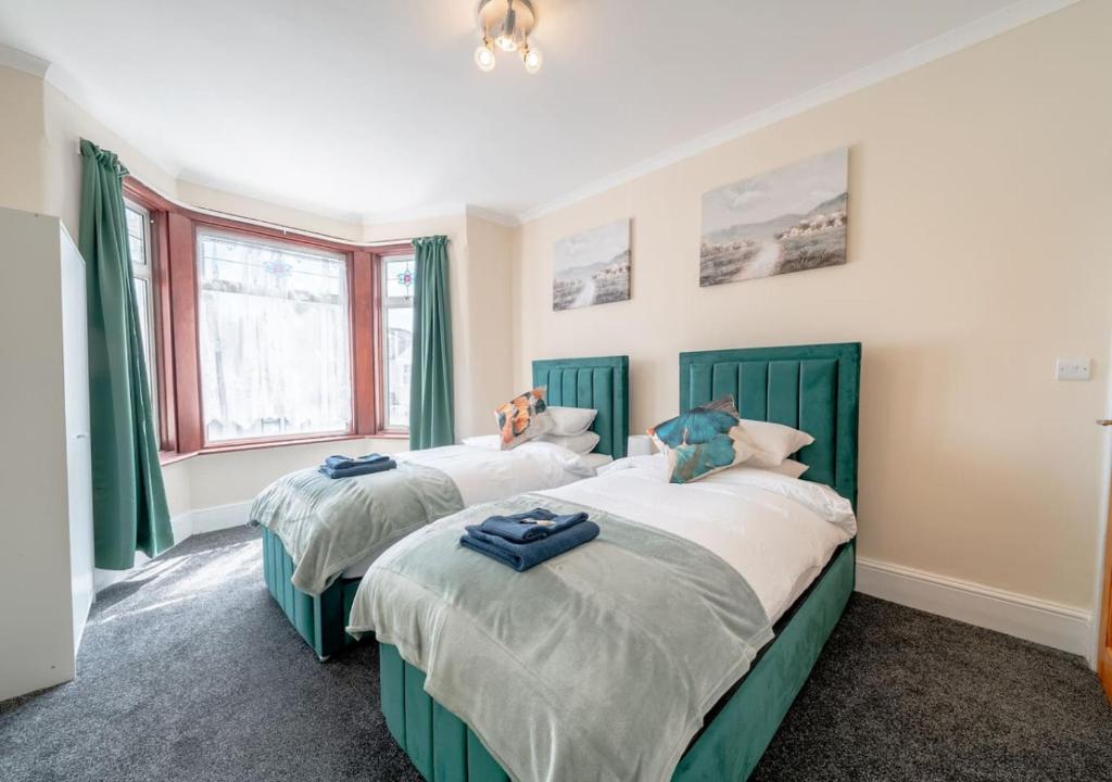 GoodmayesUksas 4 bed house Free parking的卧室设有两张单人床和绿色窗帘