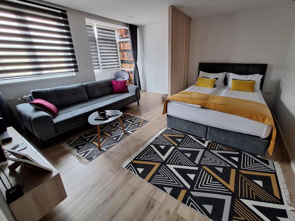 萨拉热窝Apartman Orhideja with Free Parking的一间卧室配有一张床和一张沙发