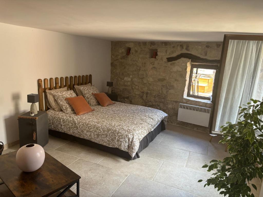 莫尔斯Chez Danièle chambre avec jacuzzi et terrasse privée的一间卧室设有一张床和石墙