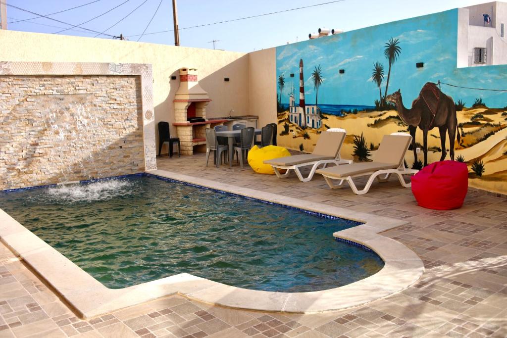 乌姆苏克Dar lamisse Djerba的一个带椅子的游泳池,海滩上还挂有壁画