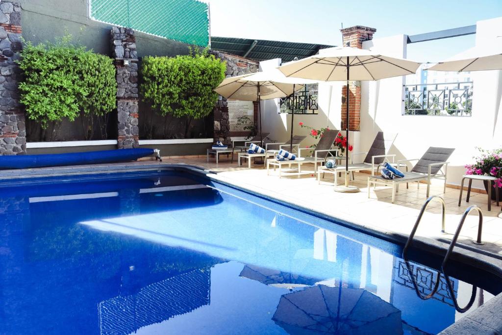 库埃纳瓦卡Hotel Borda Cuernavaca的一个带遮阳伞和桌椅的游泳池