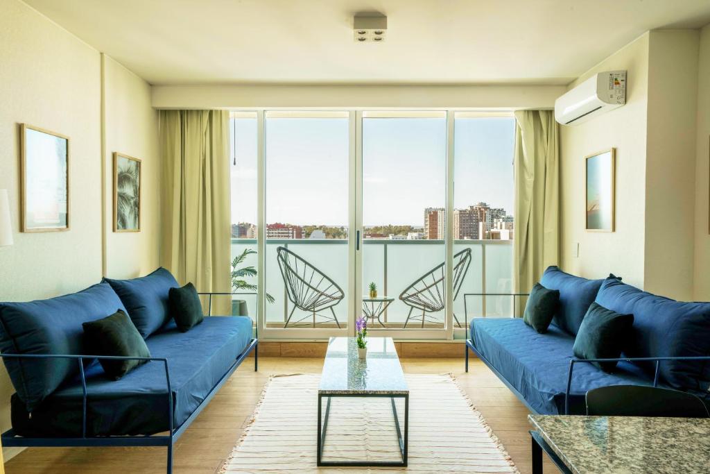 布宜诺斯艾利斯Fliphaus Be Libertador - Lux 1 Bd 11-21的客厅配有蓝色的沙发和玻璃桌