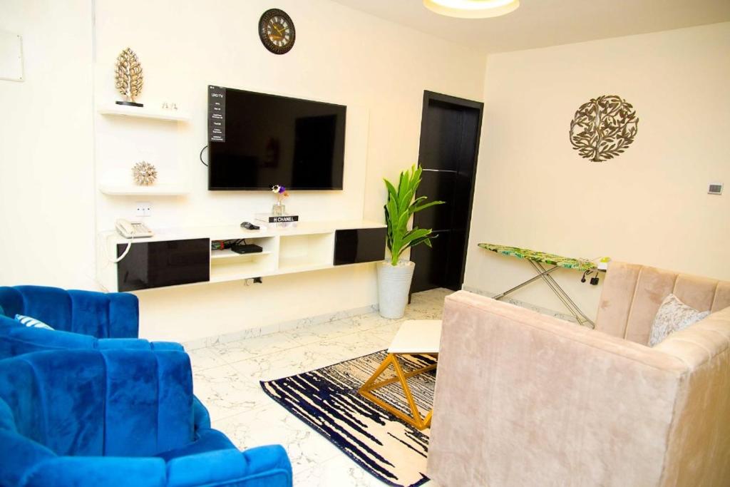 拉各斯U2 One Bedroom Apartment的客厅配有2把蓝色椅子和电视