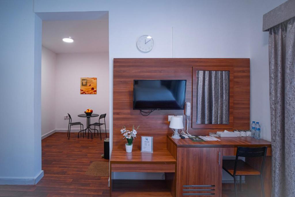 迪拜AL KARNAK HOTEL - BRANCH的客厅配有书桌、电视和桌子