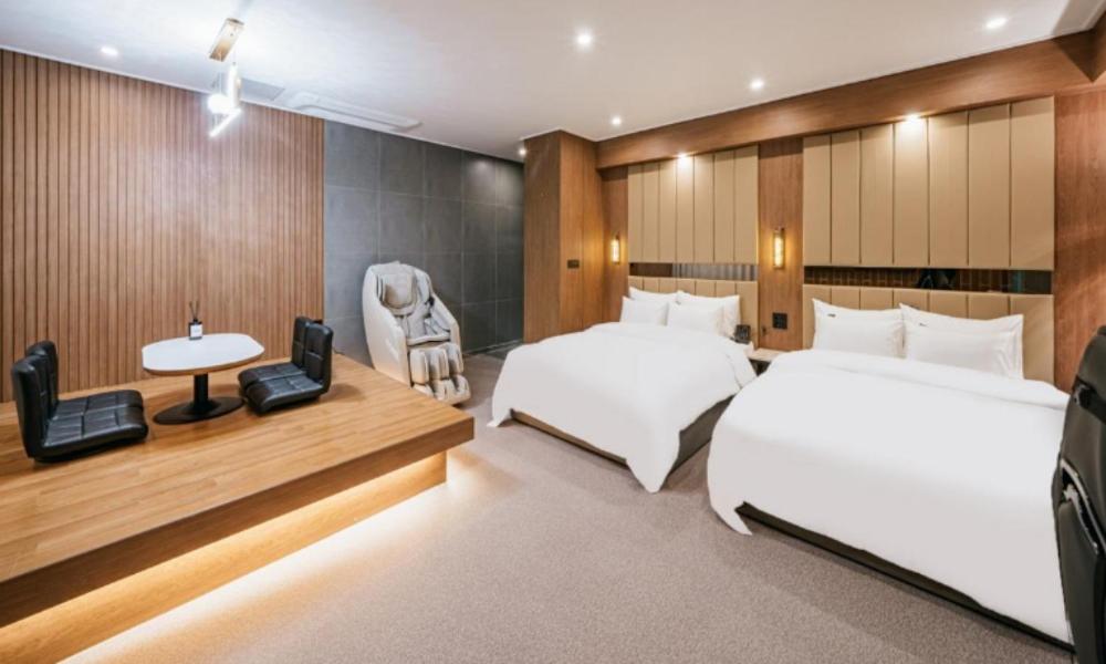 安东市Brown Dot Hotel Andong Ok-dong的一间卧室配有两张床、一张桌子和一把椅子