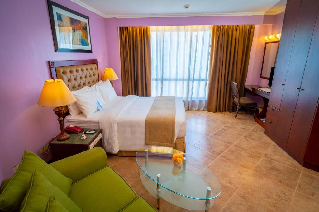 马尼拉皇家贝拉焦酒店的酒店客房,设有一张床铺和一张绿色沙发