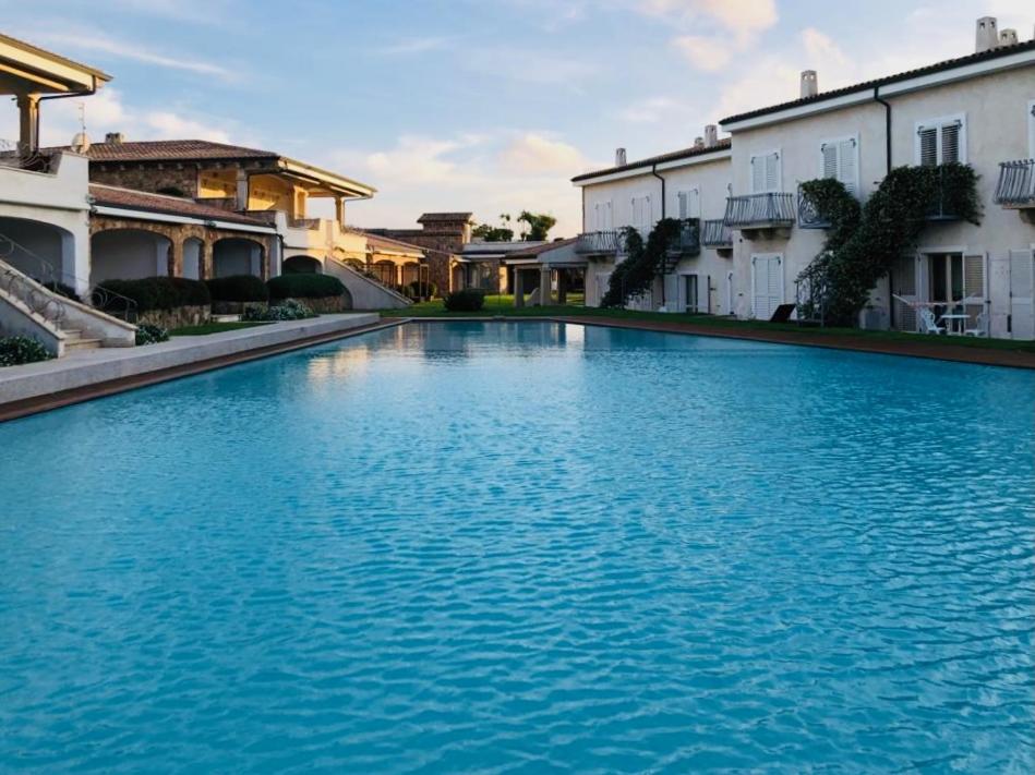 帕劳LOTUS Wellness Apartment - Resort Ginestre - Palau - Sardinia的一座大型蓝色游泳池,位于部分建筑前