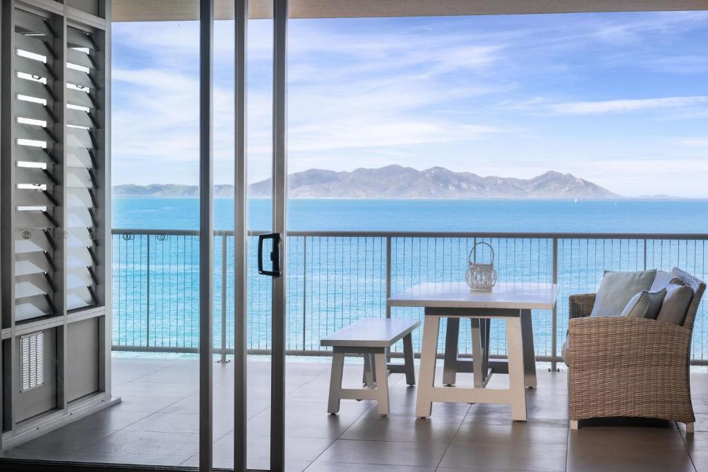 耐莉湾美爵公寓磁岛酒店的阳台配有桌子,享有海景。