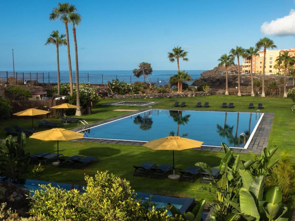圣米格尔德阿沃纳11号度假屋的享有带遮阳伞的游泳池和海洋的景致。