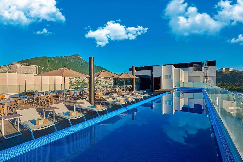 蒙特雷Radisson Hotel Monterrey San Jeronimo的一个带椅子和遮阳伞的游泳池