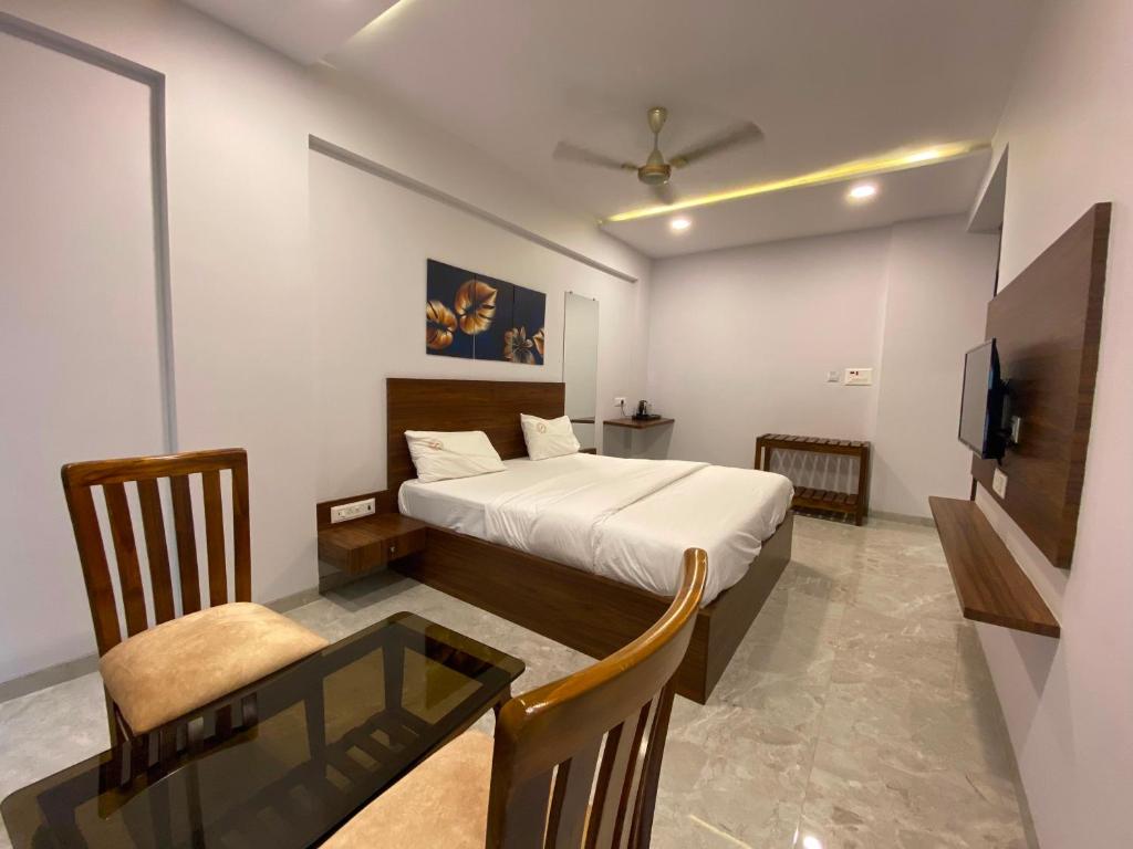 PālgharSuper OYO Flagship Hotel Swaraj的一间卧室配有一张床、一张桌子和一台电视。