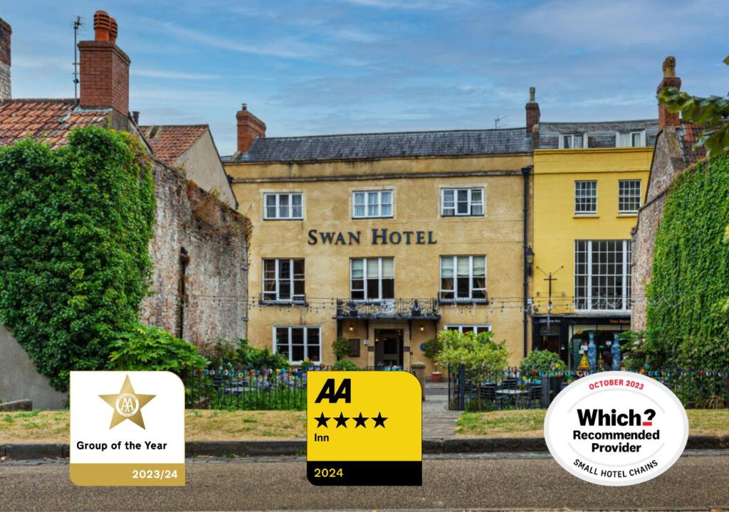韦尔斯The Swan Hotel, Wells, Somerset的一座黄色的大建筑,前面有标志