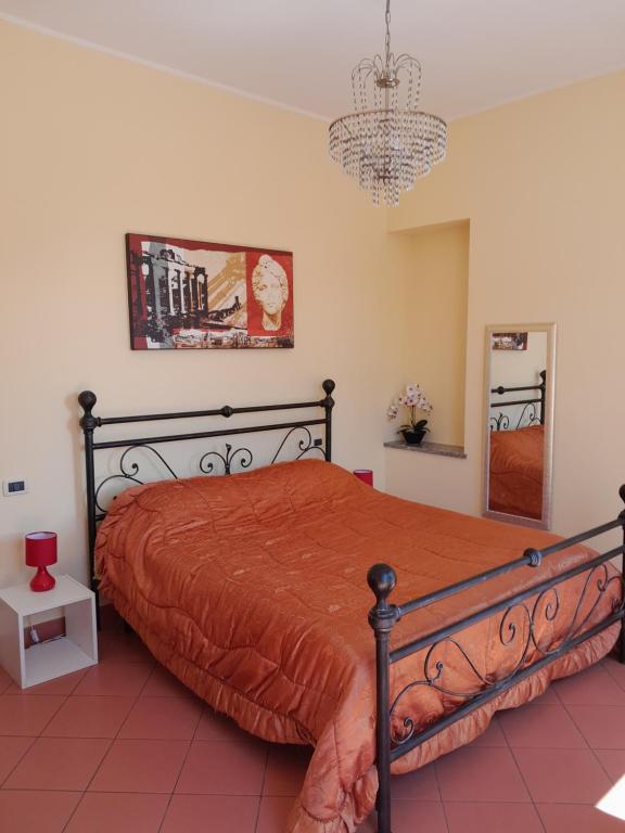 比耶拉"B&B Sans égal", con camere private e appartamenti al piano terra a Biella的一间卧室配有一张带橙色床罩和吊灯的床。