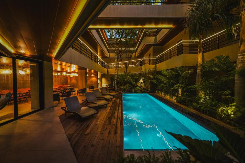 爱妮岛Piece Lio Resort from Japan的一座室内游泳池,位于一座带椅子和树木的建筑中