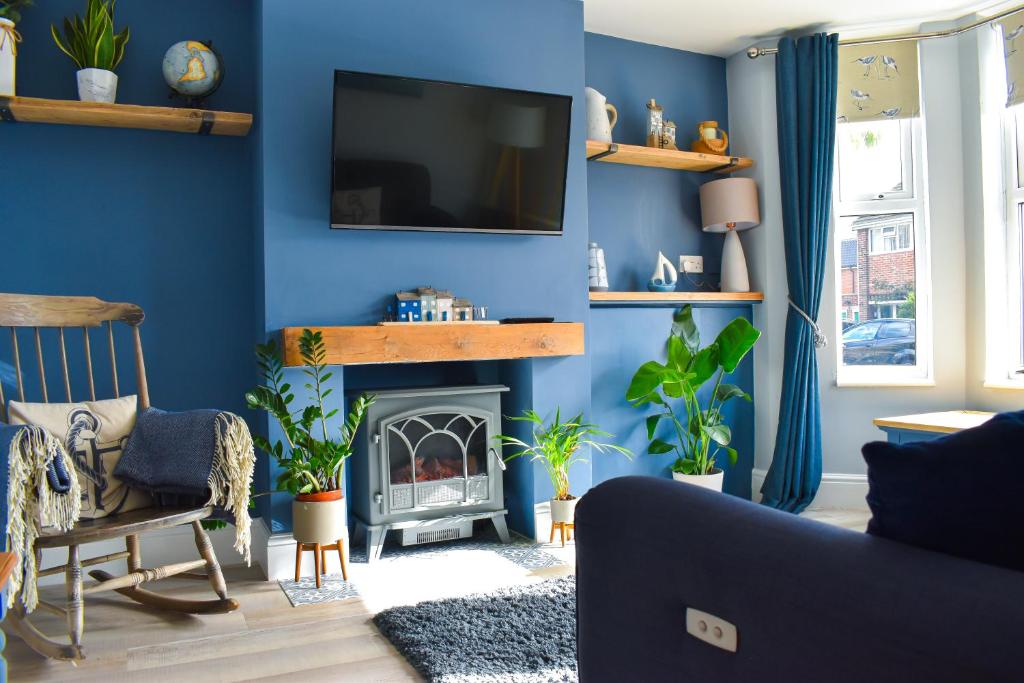 PakefieldAvocet - Suffolk Coastal Escapes的客厅设有蓝色的墙壁和壁炉。