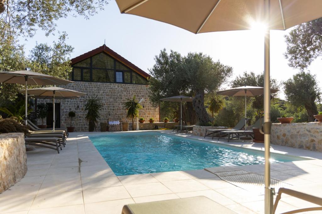 乌尔齐尼MASHTRA - The Olive House的一个带遮阳伞的游泳池和一个房子