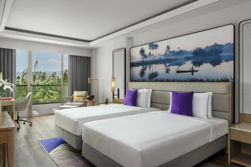 帕纳吉Vivanta Goa, Miramar的两张位于酒店客房的床铺,配有紫色枕头