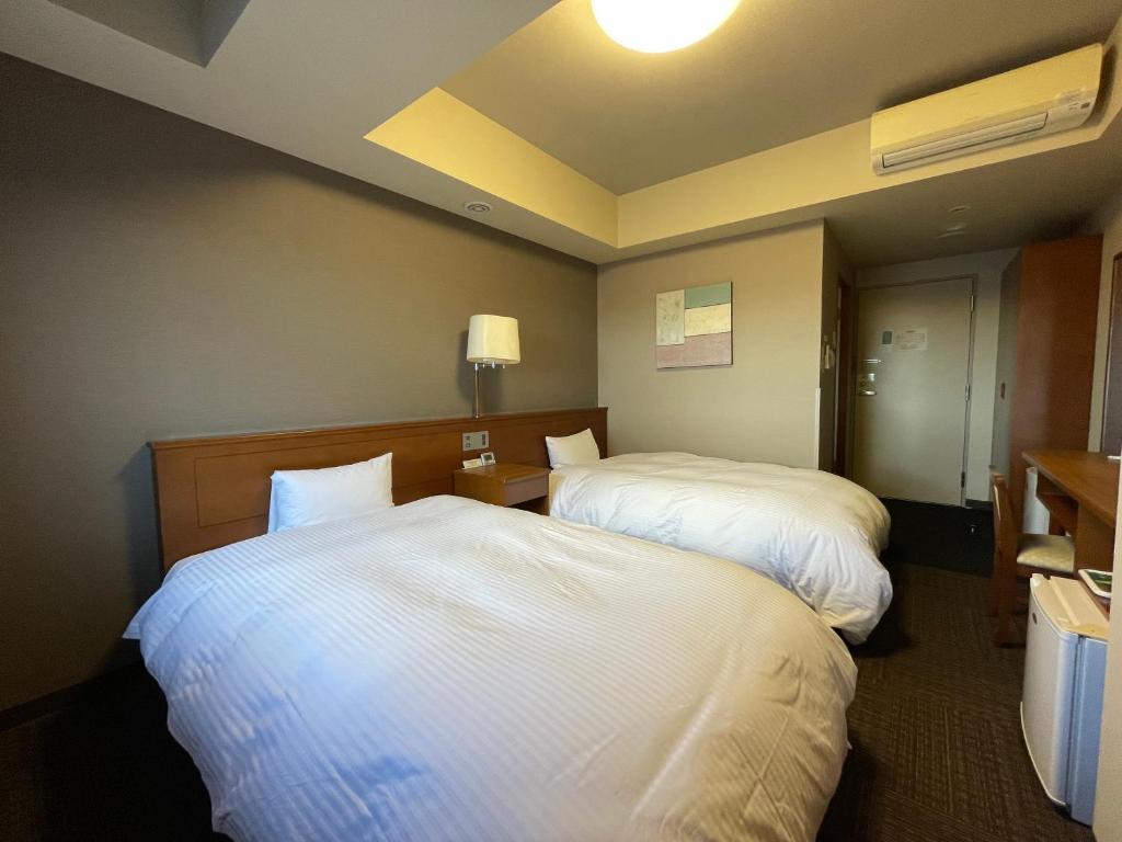 三沢市路由客栈三泽市酒店的一间酒店客房,房间内设有两张床