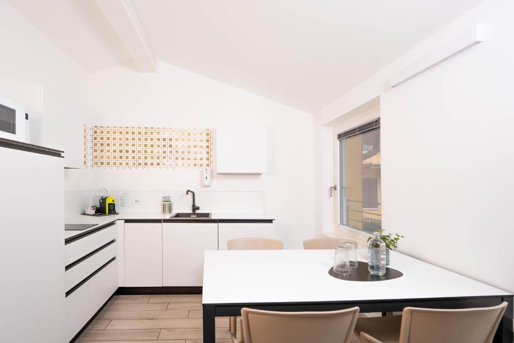 特伦托CityU - Grazioli 27 Trento Centro con parcheggio privato的白色的厨房配有桌椅