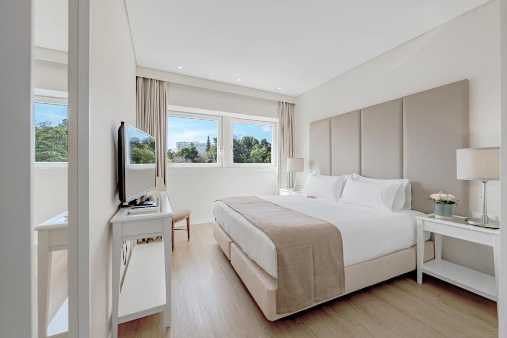 里斯本Lisboa Central Park Hotel Suites & Studios的一间白色卧室,配有床和电视