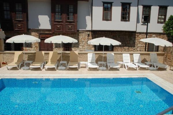 阿拉尼亚Alanya Comfort - 4 Star Beautiful Apartments between Cleopatra Beach 1 and Harbor的一座带椅子和遮阳伞的游泳池位于一座建筑旁边