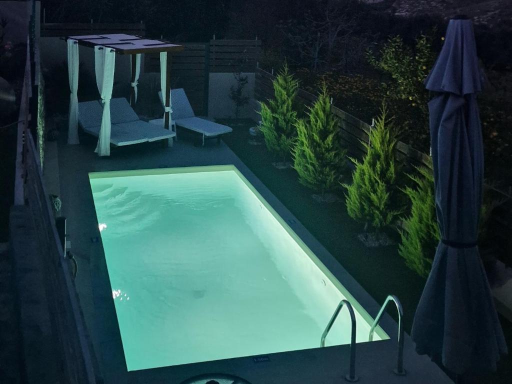 海若克利欧Elia Paradise Villa with Pool的游泳池在晚上配有桌子和遮阳伞