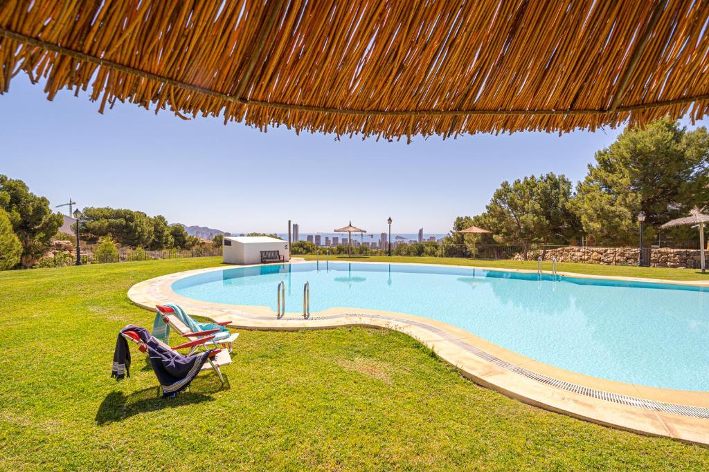 菲内斯特拉特Bahia Vista - Chalet adosado con vista al mar的一个带两把草坪椅和一把草伞的游泳池