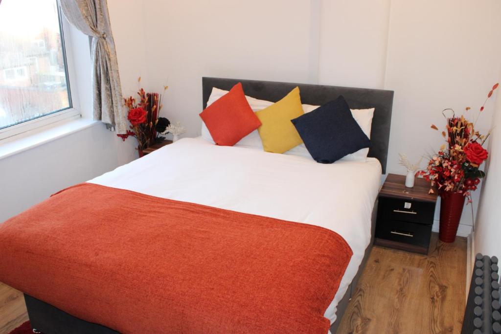 斯托克波特RB的一间卧室配有一张带色彩缤纷枕头的床和窗户。