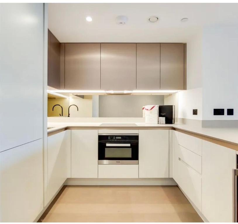 伦敦Luxury Apartment Riverside的厨房配有白色橱柜和黑烤箱。