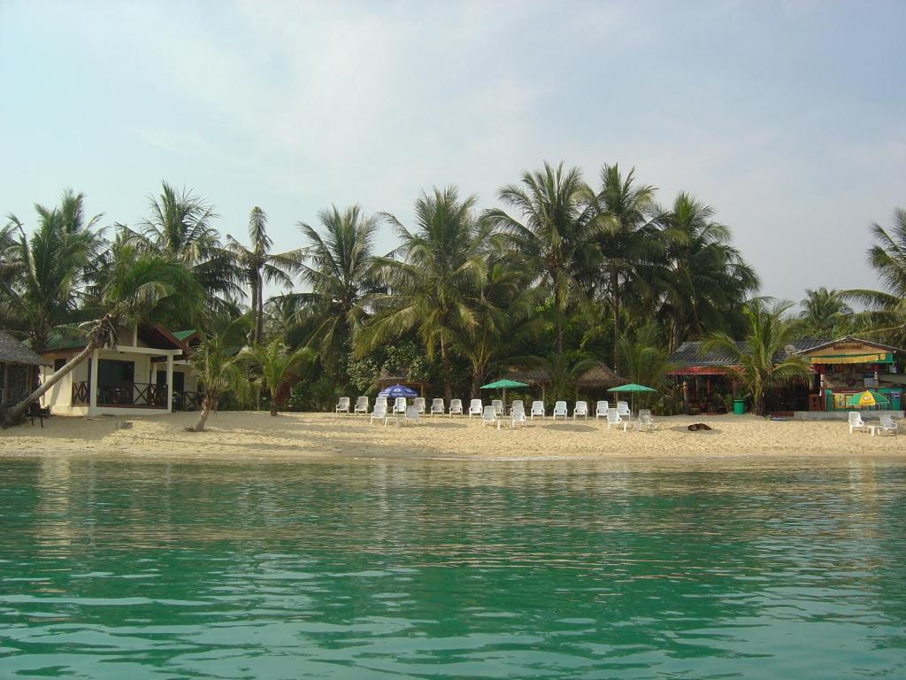 湄南海滩月亮小屋酒店的海滩上设有椅子和遮阳伞,棕榈树