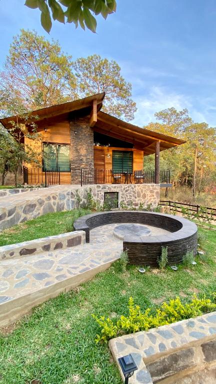 马萨米特拉Cabaña de lujo 2 habitaciones con Jacuzzi Dentro del Bosque a 10 min del Pueblo的院子里有火坑的房子