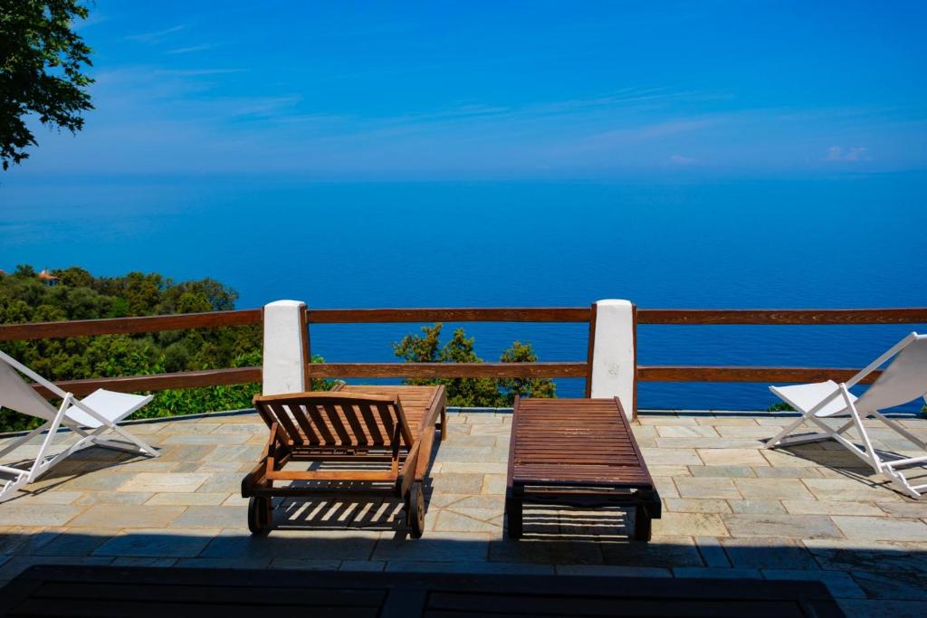达默查理Hideaway in Damouchari with private access to sea ANNA's HORIZON的两把椅子和一张长凳,位于一个享有海景的庭院