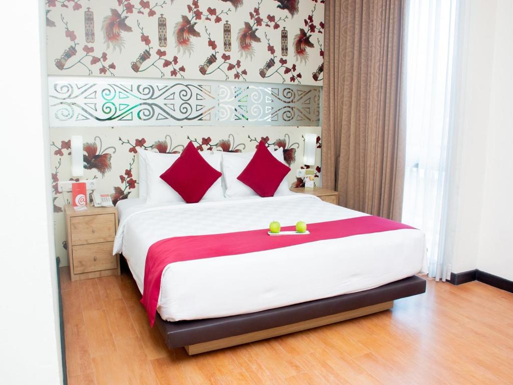 Abepura@Hom Premiere by Horison Abepura的卧室配有带红色枕头的大型白色床