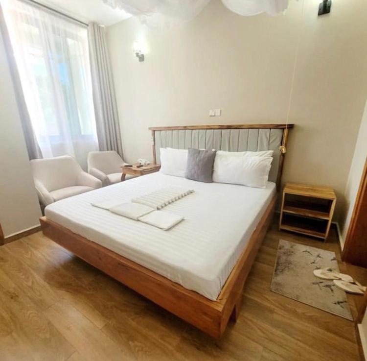 达累斯萨拉姆Lavida Inn的卧室配有一张白色大床和一把椅子