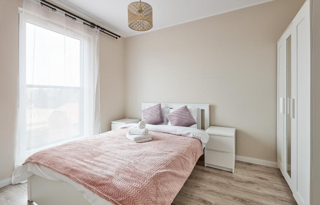 波兹南Poznań Airport Homely Apartment的白色卧室配有一张带粉色毯子的床