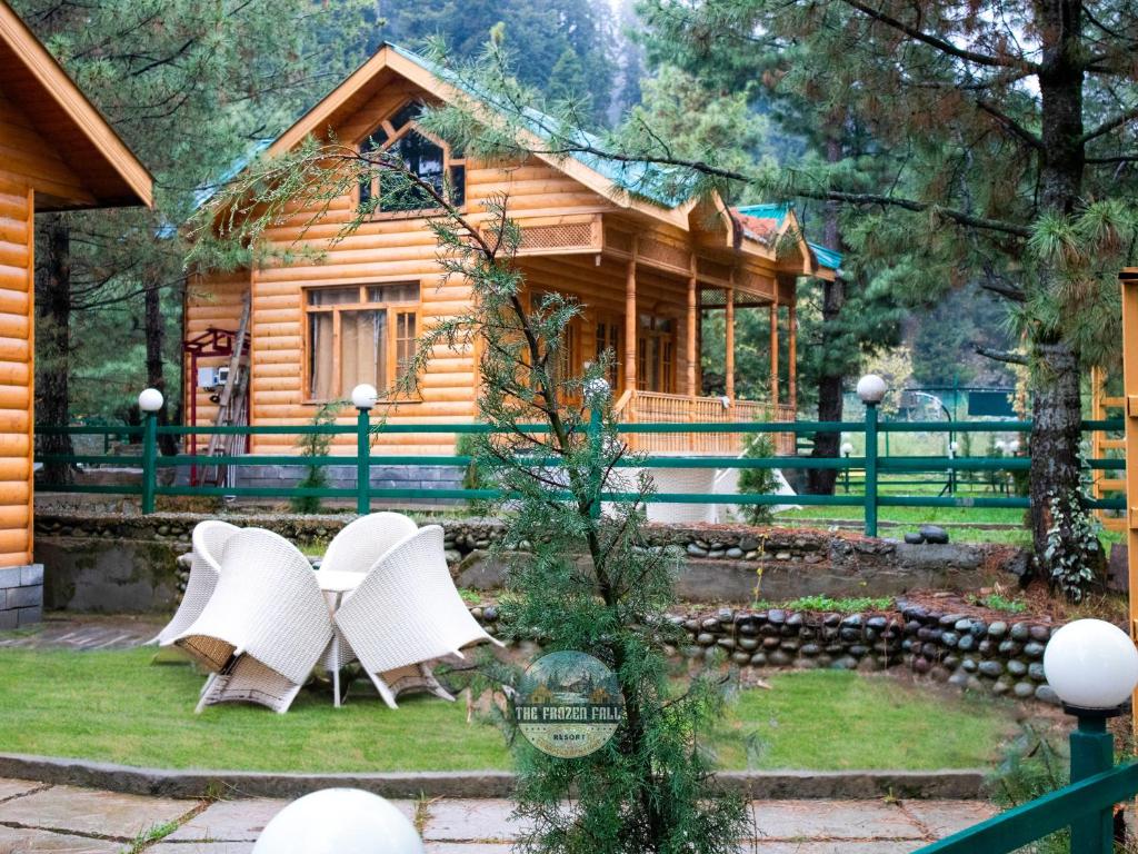 古尔马尔格The Frozenfall Resort的前面的木屋配有白色椅子