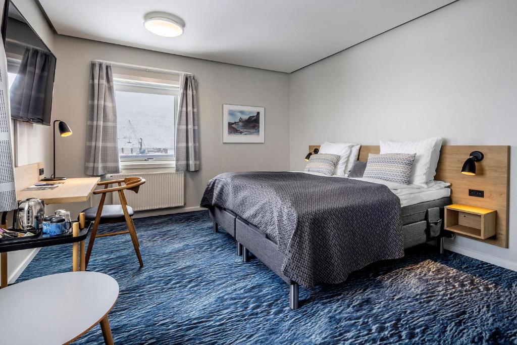 努克HOTEL SØMA Nuuk的一间卧室配有一张床、一张书桌和一个窗户。