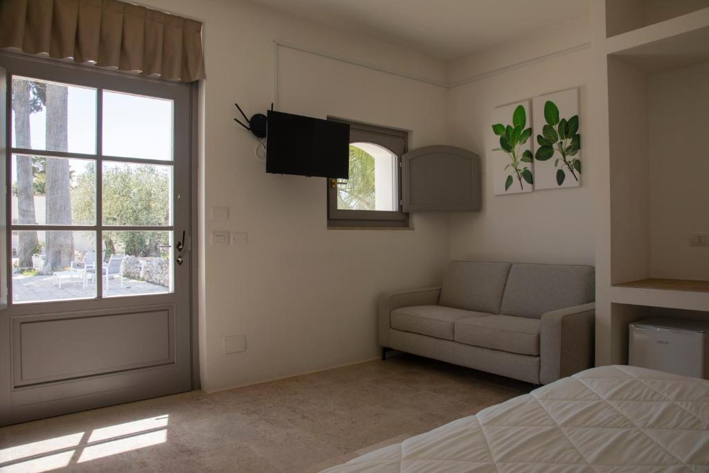 圣塞韦罗Masseria Celentano Relais & Agriturismo的一间卧室配有一张床、一张沙发和一个窗口