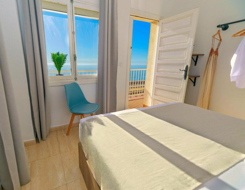 阿桂拉斯Maxcaly Playa的卧室配有床、椅子和窗户。