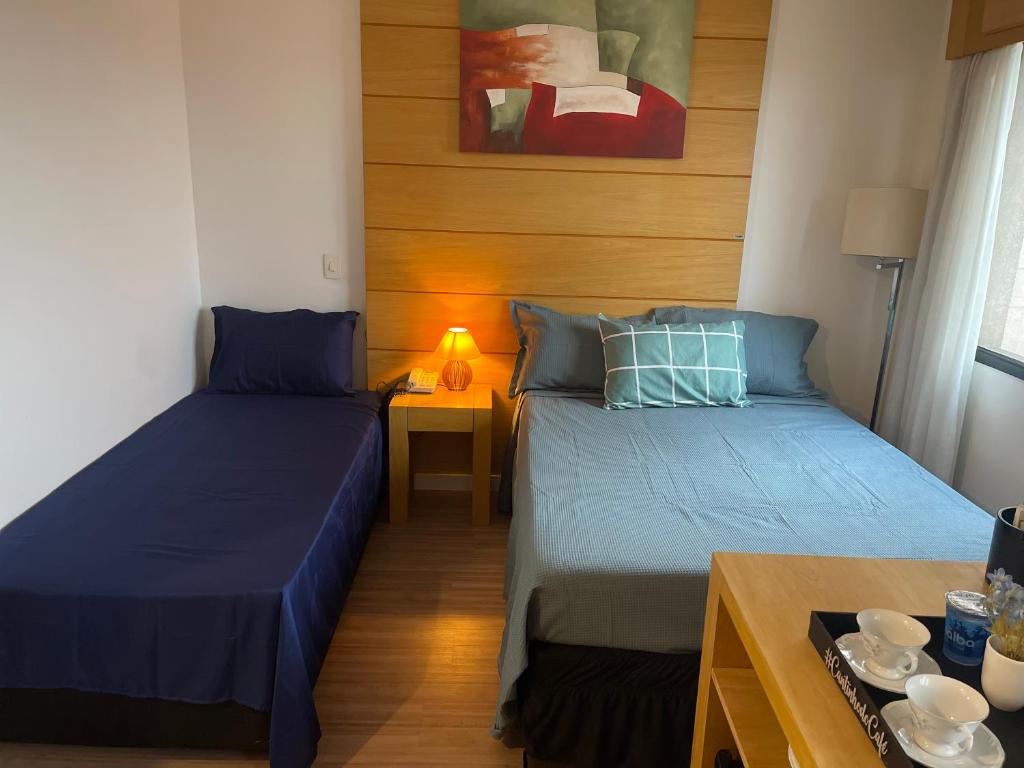圣保罗Flat de Luxo Aeroporto Congonhas - Hotel eSuites的小房间设有两张床和一张桌子