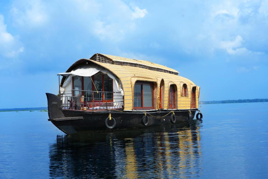 阿勒皮Aqua Castle Houseboat - by Aqua Jumbo Houseboats的木船坐在水面上