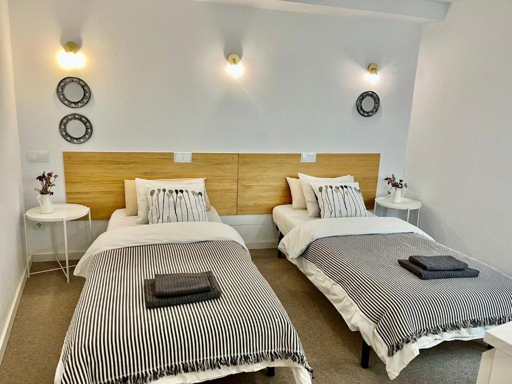阿利坎特Hola Hostel Alicante的墙上挂有时钟的房间里设有两张床