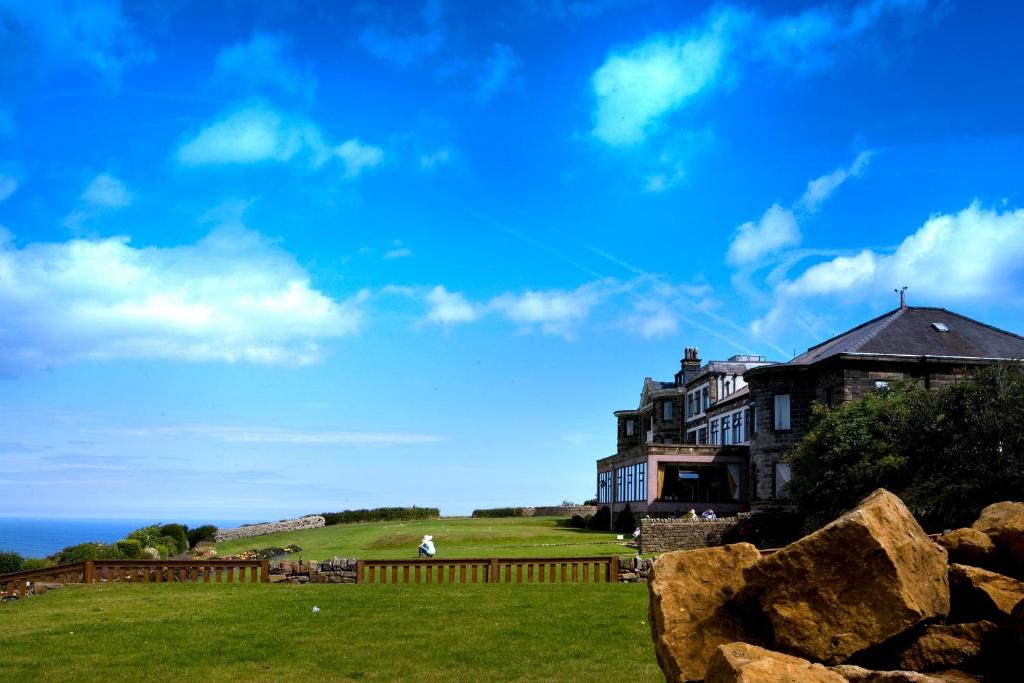 雷文斯卡雷文厅酒店的一座山丘上的房屋,背景是大海