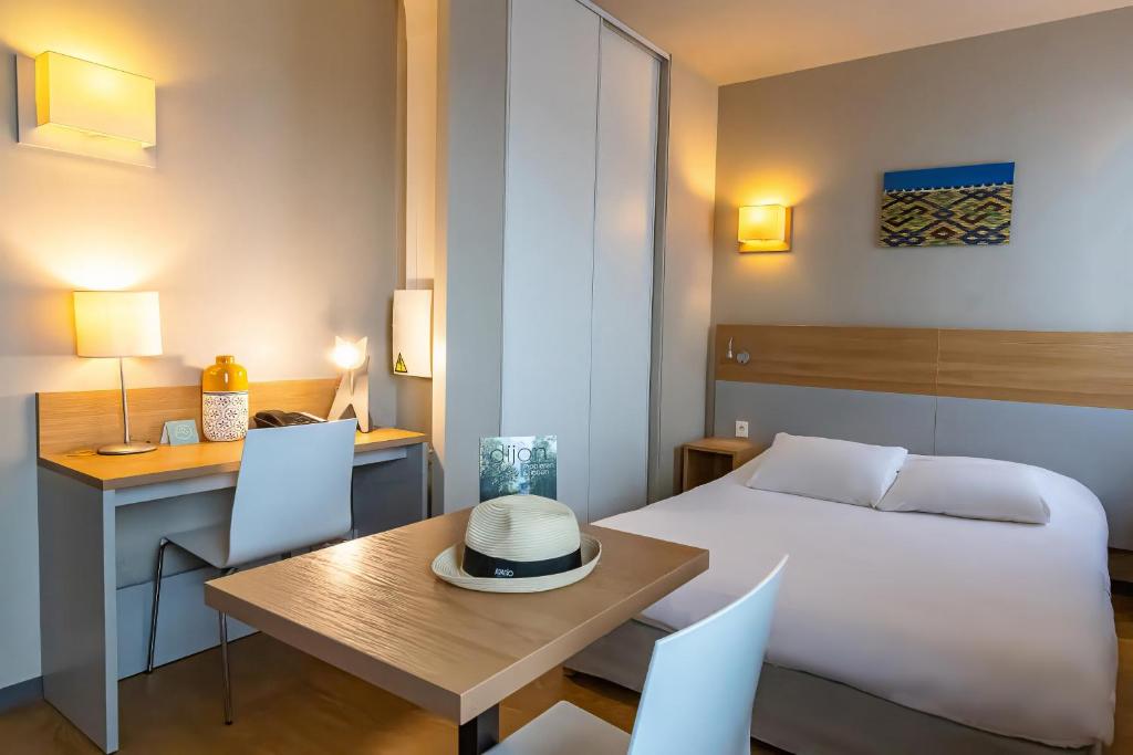 第戎第戎共和国广场阿达吉公寓式酒店的酒店客房配有一张床铺、一张桌子和一张书桌。