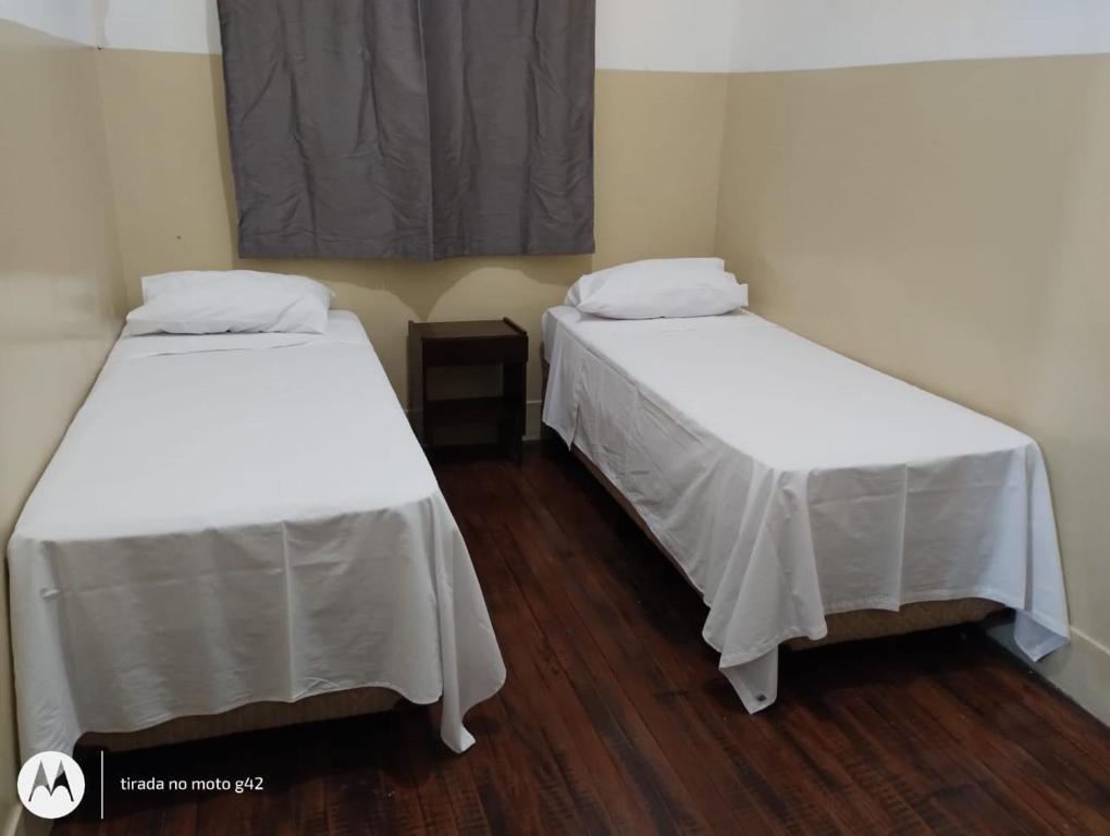 阿拉萨图巴Hotel Central的配有白色床单的客房内的两张床