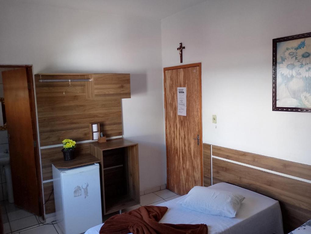 阿帕雷西达Hotel Portal dos anjos的一间设有一张床的客房,墙上有十字架