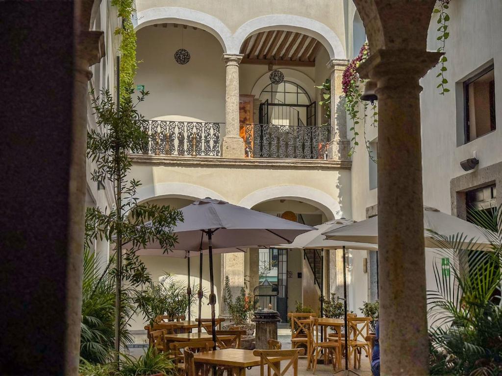 瓜达拉哈拉Palpatio Hotel的一座建筑中带桌子和遮阳伞的庭院